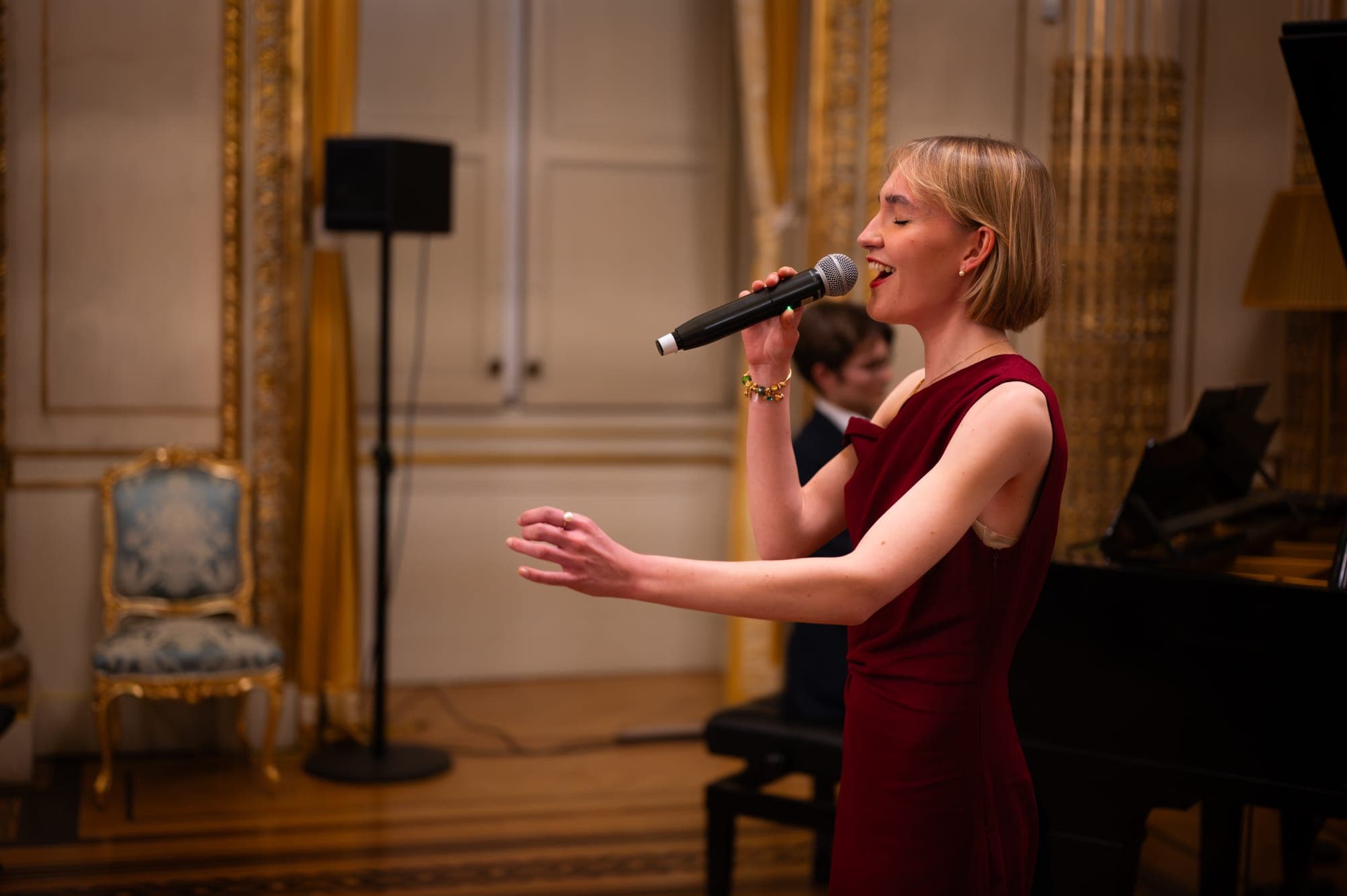 A singer in a red dress performing with a pianist