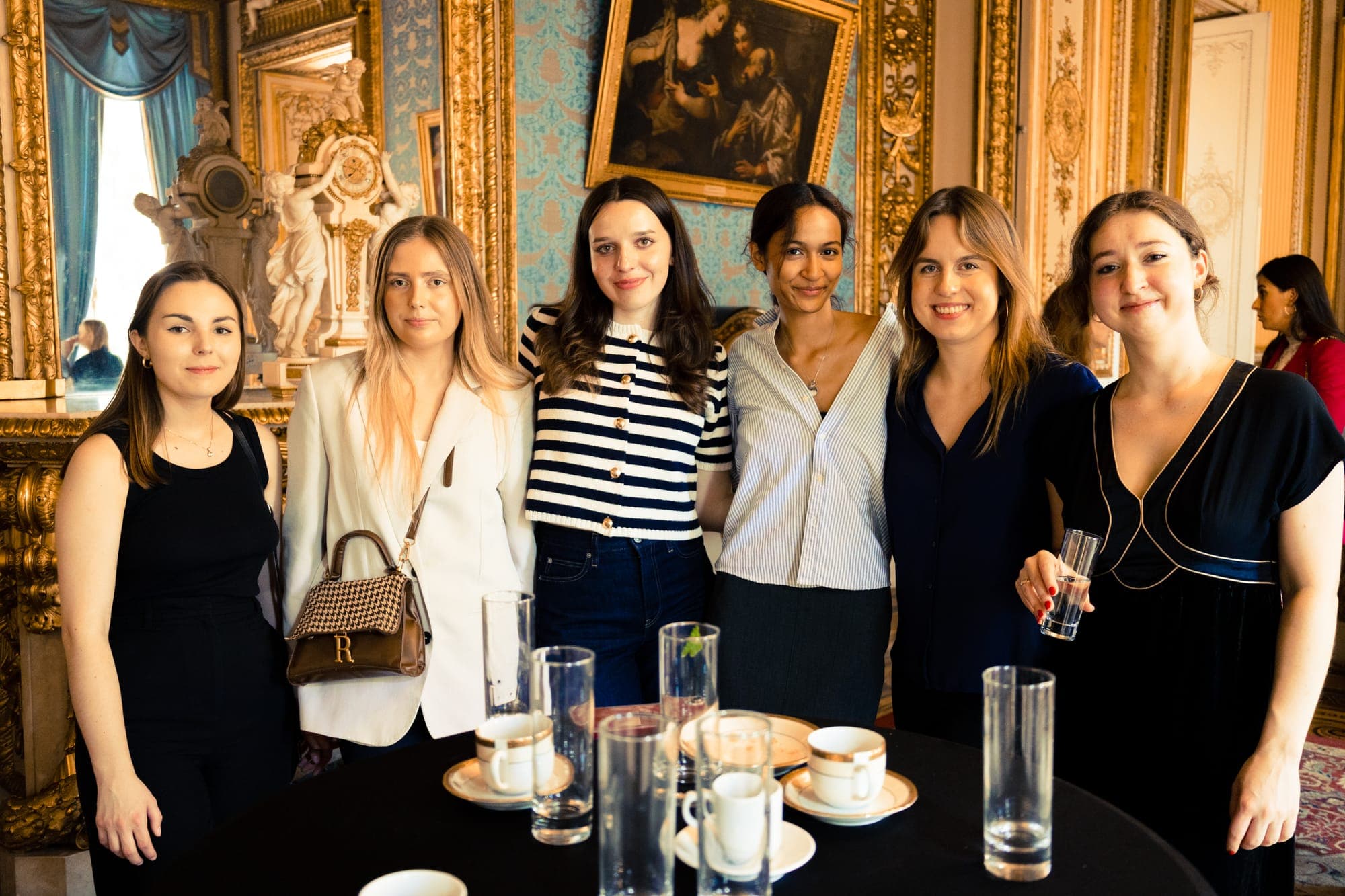 A group of guests around a coffee table in a blue and gold salon