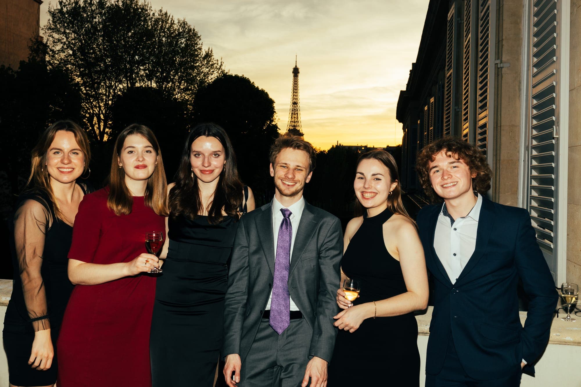 Guests gathered on a terrace at sunset with the Eiffel Tower in the distance
