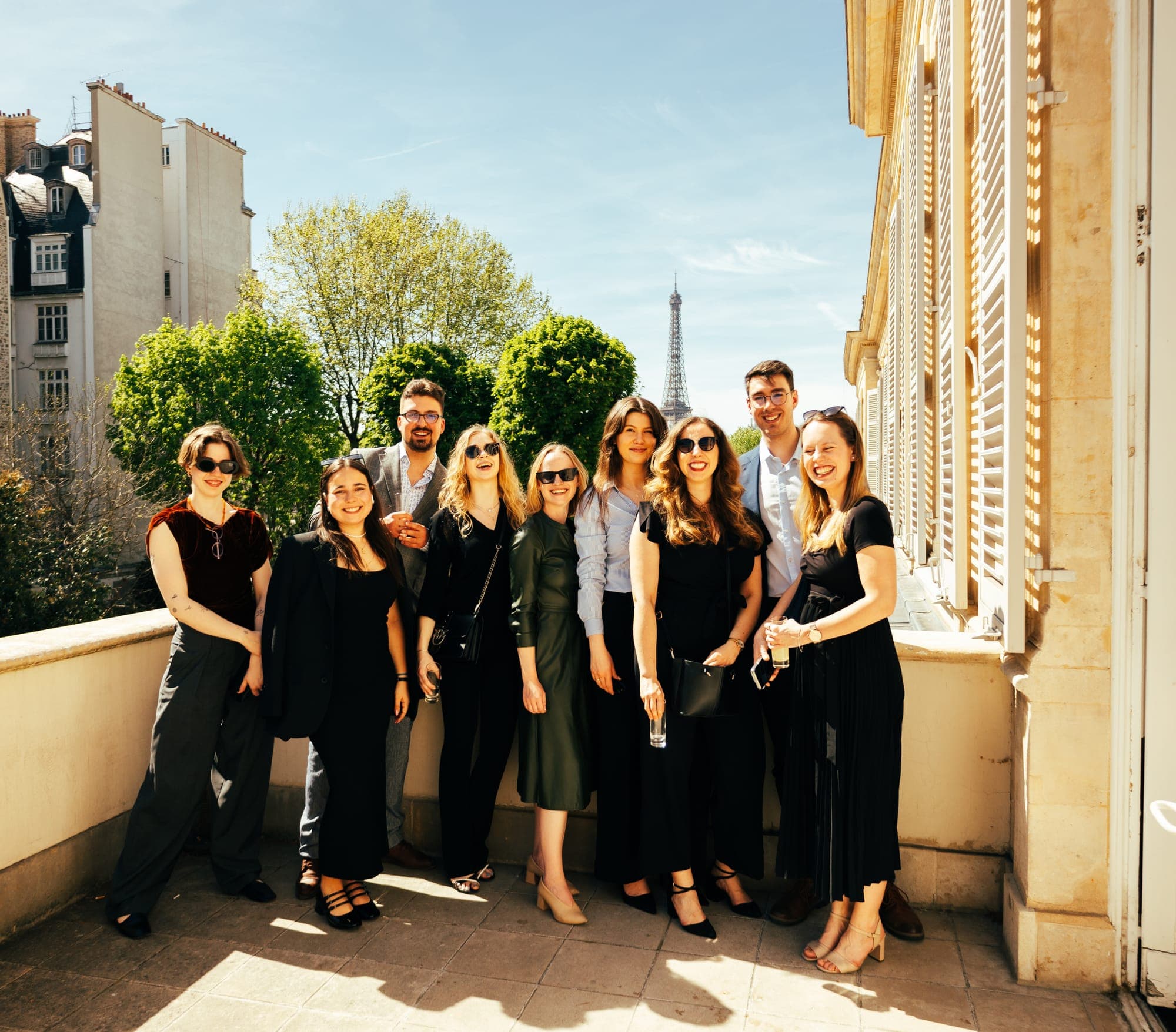 Young guests posing together on a sunny terrace with the Eiffel Tower behind